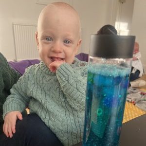 child smiling at a sensory bottle
